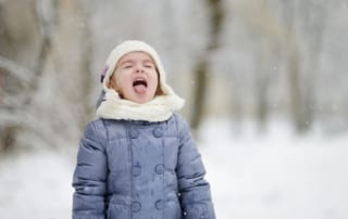 Little girl catching snowflakes.