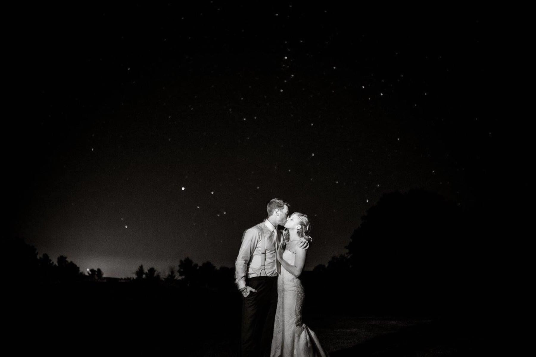 Bride and Groom kissing under a starry sky.