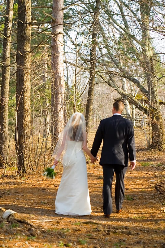 Bride and Groom walking in the woods.