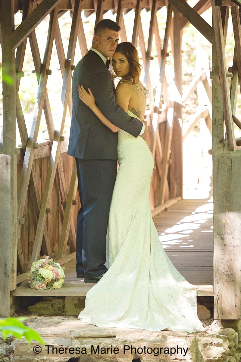 Bride and Groom standing on covered bridge.