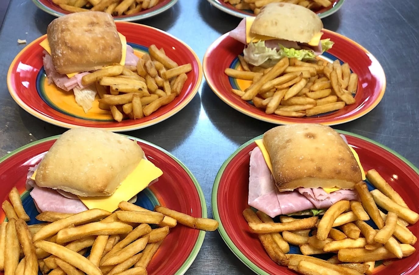 Sandwiches and fries on colorful plates. 