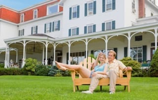 Couple sitting on wooden loveseat on the lawn.