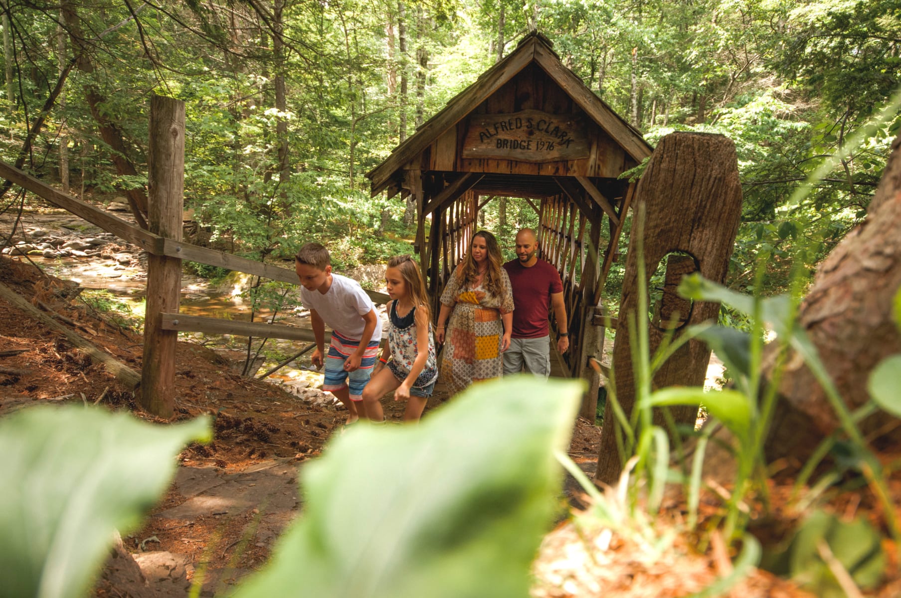 Family hiking through covered bridge