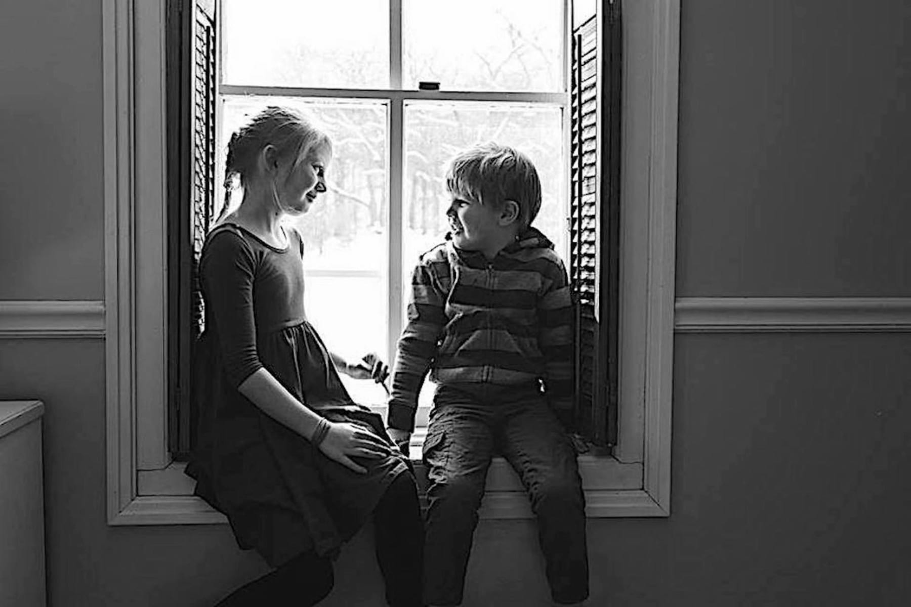 Boy and girl sitting in a windowsill.